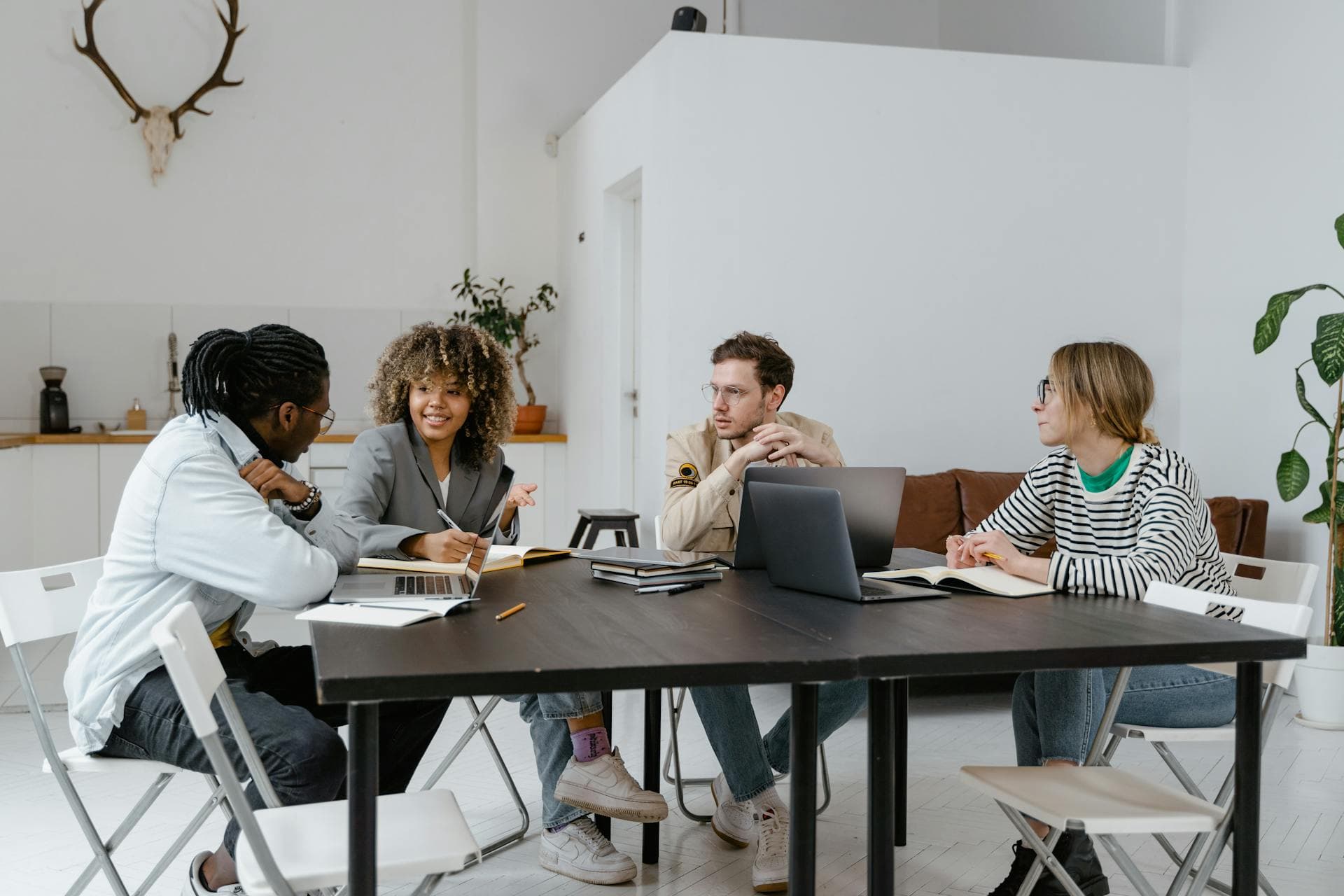 Equipo de profesionales en oficina durante una reunión de negocio, con un directivo senior orientando la conversación